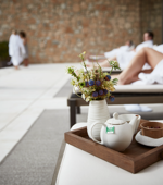 Tea pot on wooden tray with small vase of flowers on day bed at luxuty 5* hotel in Girona