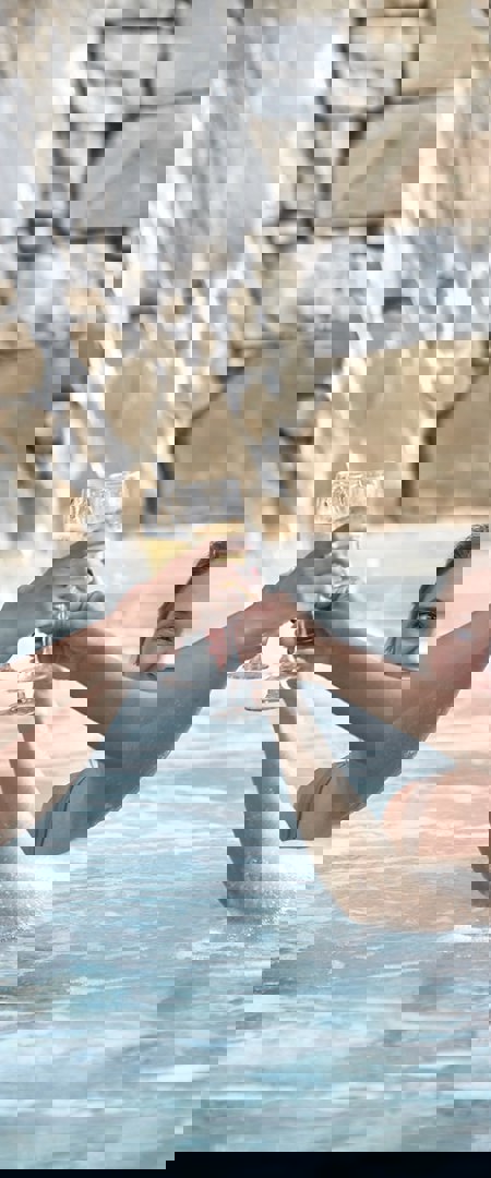 Four women cheers champagne glasses in pool at Camiral luxury 5* resort