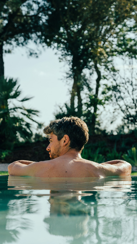 Man Swimming in blue water pool at Camiral resort Wellness Spa near Costa Brava