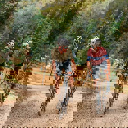 Two Cyclists Riding Gravel Bikes Through Forest Trails at PGA Catalunya Resort in Girona