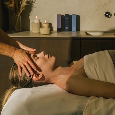 Facial massage with woman on massage table in elegant massage room with candles and soft light
