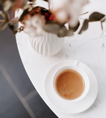 White marble table with white porcelain tea cup and red flowers in luxury setting