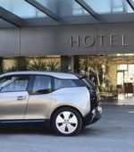 A sleek silver BMW electric car parked at the luxury Hotel Camiral entrance.