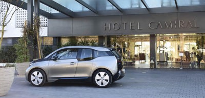 A sleek silver BMW electric car parked at the luxury Hotel Camiral entrance.