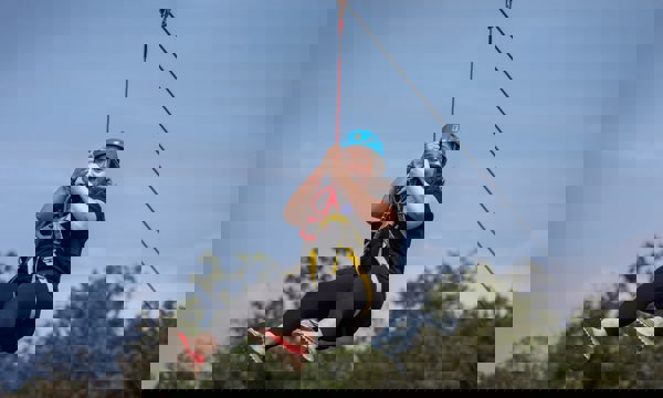 Woman on zipline with blue helmet moving along wire