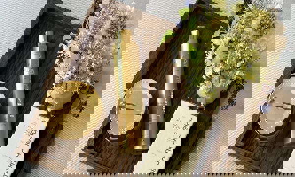 Gold Miriam Quevedo beauty products on elegant wooden tray on grey cushion