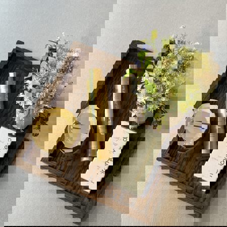 Gold Miriam Quevedo beauty products on elegant wooden tray on grey cushion