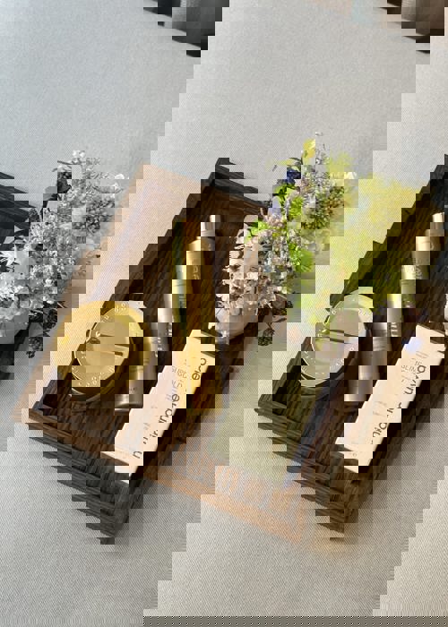 Gold Miriam Quevedo beauty products on elegant wooden tray on grey cushion