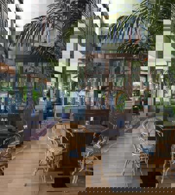 Stylish Indoor Lounge and Dining Area with Tropical Plants at Camiral Bistro